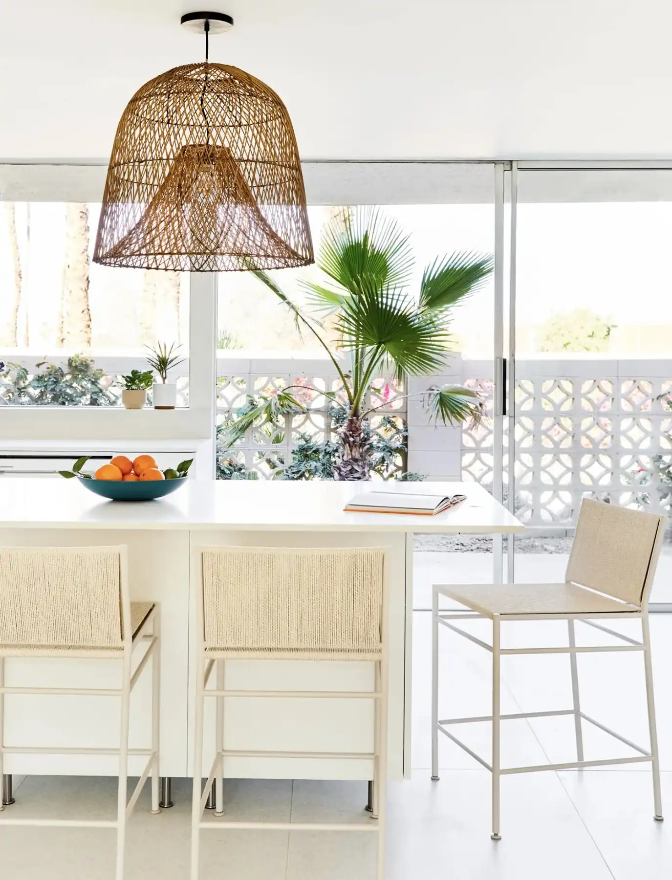 Kitchen island under a rattan pendant with breeze block beyond, Sandpiper condo, Palm Desert