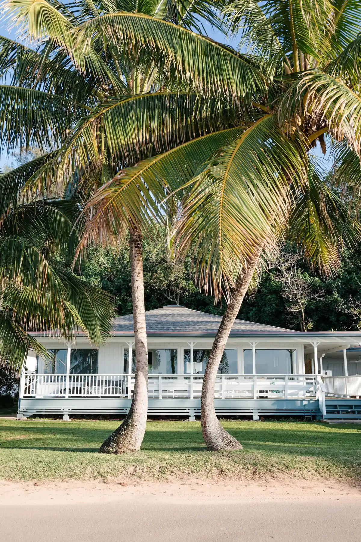White beachfront cottage framed by palms, Anini Beach, Kauai