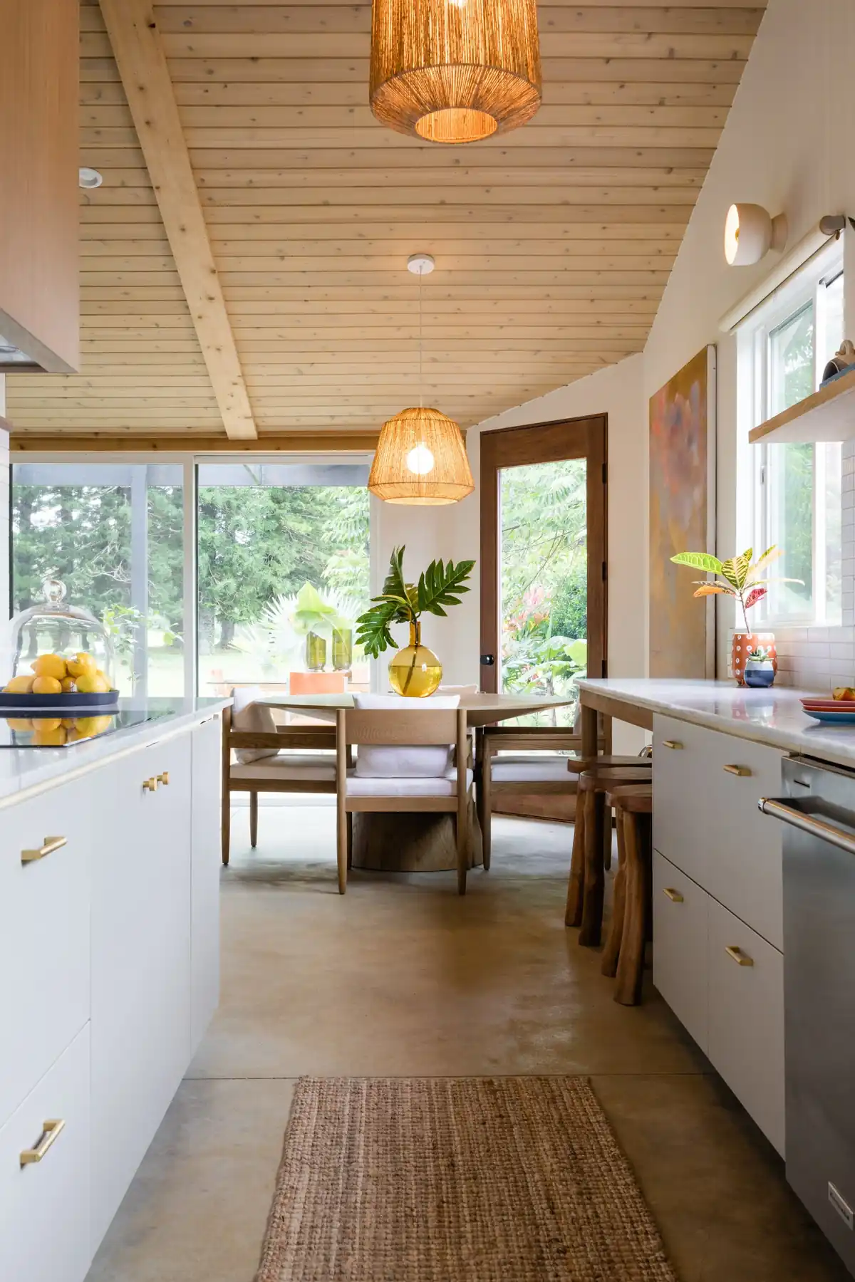 A renovated kitchen with pale timber ceiling, custom cabinetry, and woven pendant